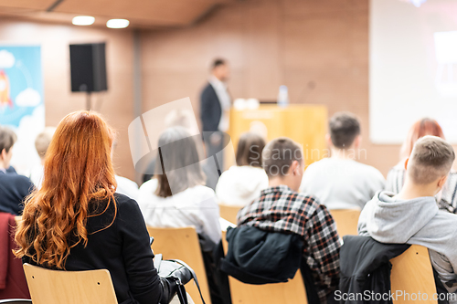 Image of Speaker giving a talk in conference hall at business event. Rear view of unrecognizable people in audience at the conference hall. Business and entrepreneurship concept.