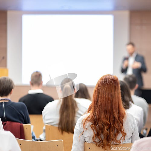 Image of Speaker giving a talk in conference hall at business event. Rear view of unrecognizable people in audience at the conference hall. Business and entrepreneurship concept.