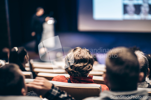 Image of Speaker giving a talk in conference hall at business event. Rear view of unrecognizable people in audience at the conference hall. Business and entrepreneurship concept.