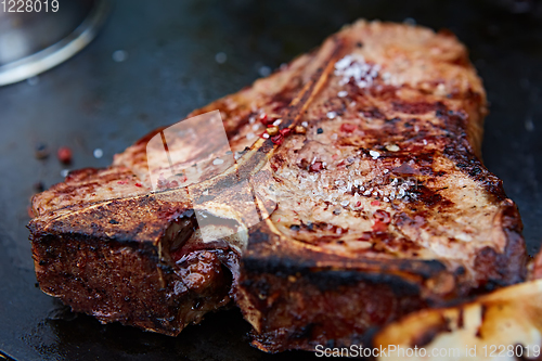 Image of Grilled T-Bone Steak on serving board on wooden background