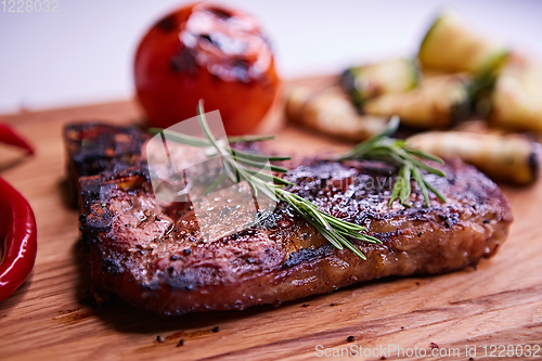 Image of Grilled T-Bone Steak on serving board on wooden background