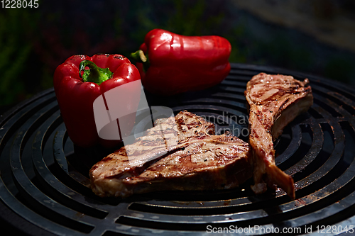 Image of Tomahawk rib beef steak and T-bone on hot black grill.