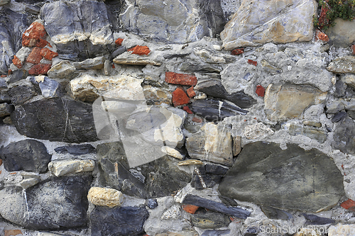 Image of Vintage wall from stones of various shapes and red bricks