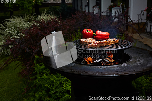 Image of Tomahawk rib beef steak and T-bone on hot black grill.