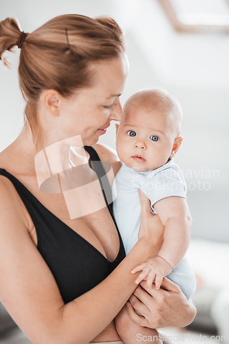 Image of Portrait of sweet baby resting in mothers arms, looking at camera. New mom holding and cuddling little kid, embracing child with tenderness, love, care. Motherhood concept