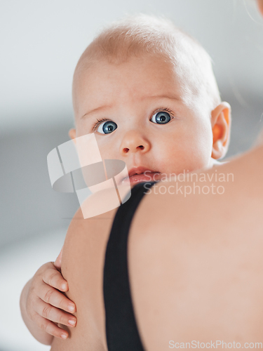 Image of Portrait of sweet baby resting in mothers arms, looking at camera, touching mama shoulder. New mom holding little kid, embracing child with tenderness, love, care. Motherhood concept