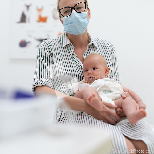 Image of Mother holding her baby boy at medical appointment at pediatrician office.