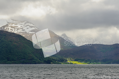 Image of snow-covered mountains with green trees and rays of sunlight bre