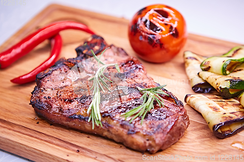 Image of Grilled T-Bone Steak on serving board on wooden background