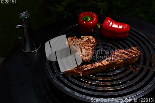 Image of Tomahawk rib beef steak and T-bone on hot black grill.