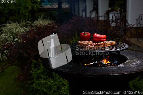 Image of Tomahawk rib beef steak and T-bone on hot black grill.