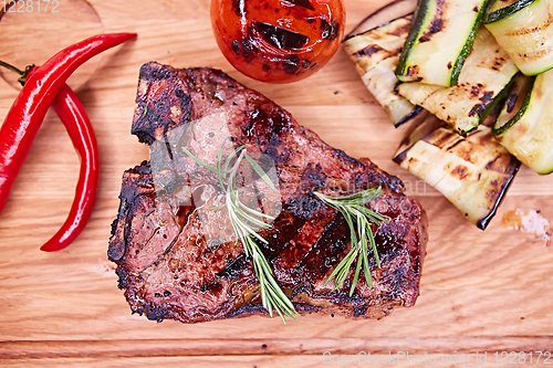 Image of Grilled T-Bone Steak on serving board on wooden background