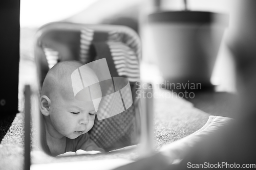 Image of Beautiful shot of a cute baby boy looking at his reflection in the mirror. Black and white image.