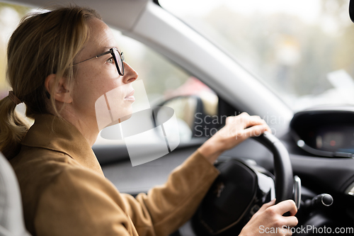 Image of Business woman driving a car to work. Female driver steering car on the road