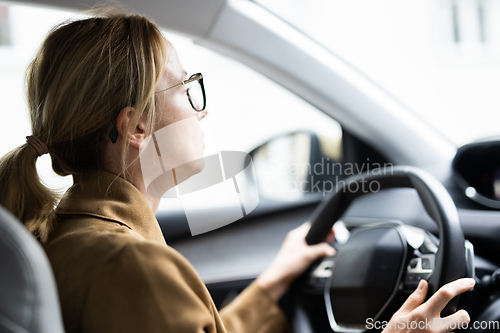 Image of Business woman driving a car to work. Female driver steering car on the road