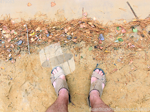 Image of feet of the traveller standing on the sand