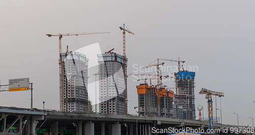 Image of Many of cranes. Tower cranes against blue sky, with clouds