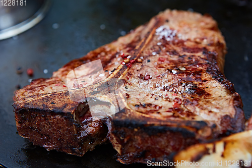 Image of Grilled T-Bone Steak on serving board on wooden background