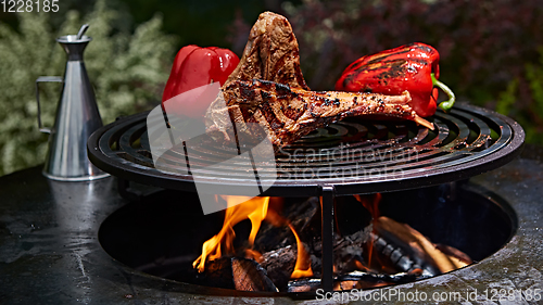 Image of Tomahawk rib beef steak and T-bone on hot black grill.