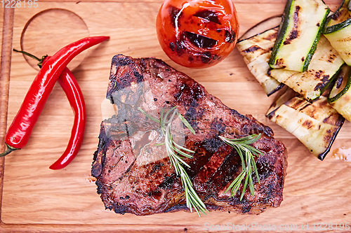 Image of Grilled T-Bone Steak on serving board on wooden background