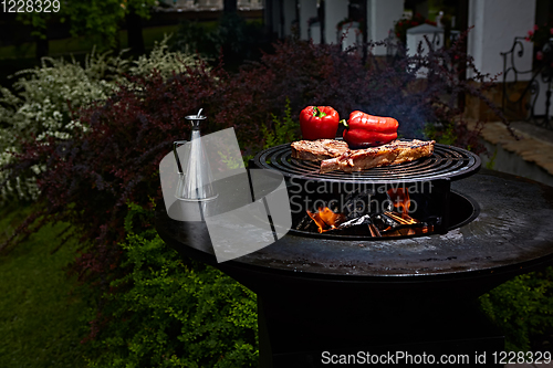 Image of Tomahawk rib beef steak and T-bone on hot black grill.