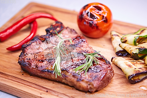 Image of Grilled T-Bone Steak on serving board on wooden background