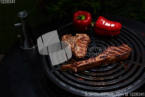 Image of Tomahawk rib beef steak and T-bone on hot black grill.