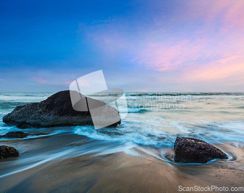 Image of waves and rocks on beach of sunset