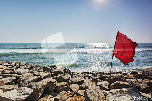 Image of Red flag on rocky beach