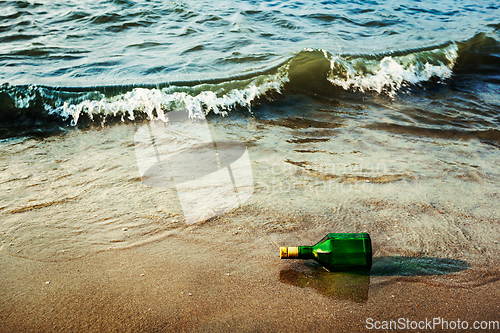 Image of Message bottle on beach in waves