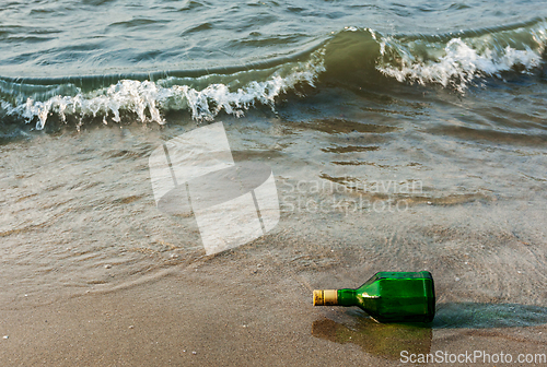 Image of Message bottle on beach in waves