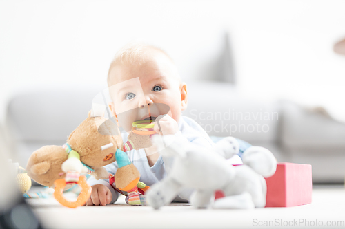 Image of Cute baby boy playing with toys on mat at home Baby activity and play center for early infant development. Baby playing at home.