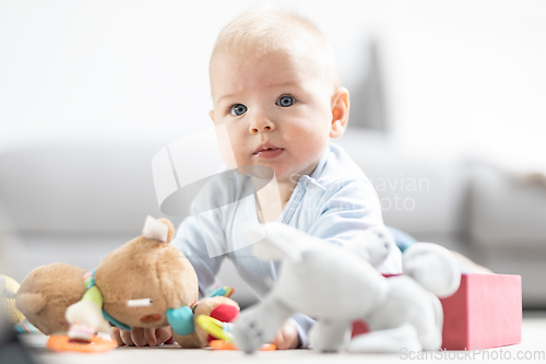 Image of Cute baby boy playing with toys on mat at home Baby activity and play center for early infant development. Baby playing at home.