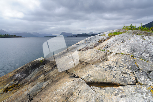 Image of rock formations by the sea and boats passing by