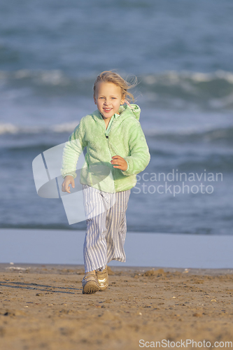 Image of The girl is running along the beach by the sea