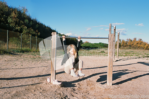 Image of Little girl hanging on the horizontal bar