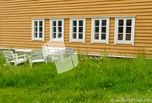 Image of seating area in field in front of yellow old building