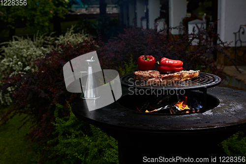 Image of Tomahawk rib beef steak and T-bone on hot black grill.