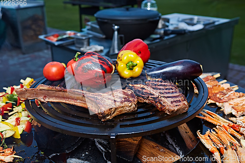 Image of Tomahawk rib beef steak and T-bone on hot black grill.