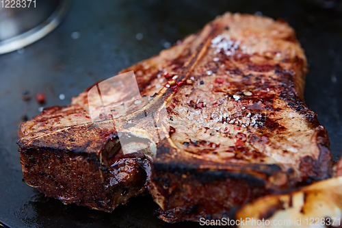 Image of Grilled T-Bone Steak on serving board on wooden background