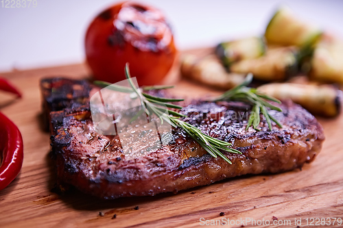 Image of Grilled T-Bone Steak on serving board on wooden background