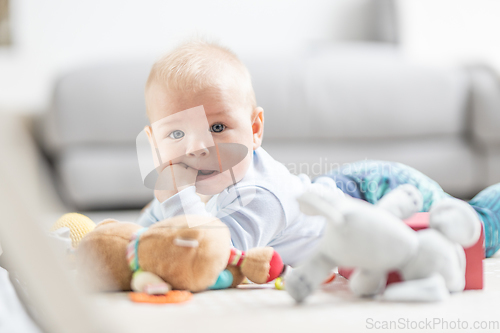 Image of Cute baby boy playing with hanging toys arch on mat at home Baby activity and play center for early infant development. Baby playing at home