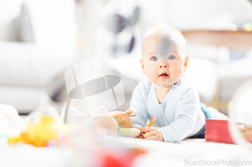 Image of Cute baby boy playing with hanging toys arch on mat at home Baby activity and play center for early infant development. Baby playing at home