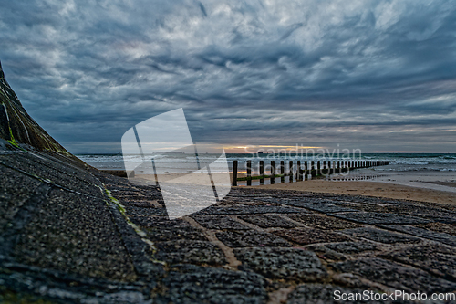 Image of Dramatic seascape with feather clouds. Rocky coastline with wooden breakwaters