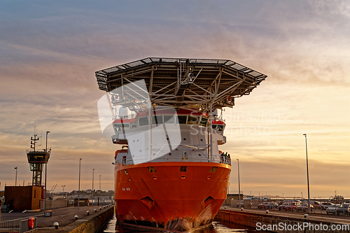 Image of A huge merchant sea vessel in the port lock against the sky at sunset