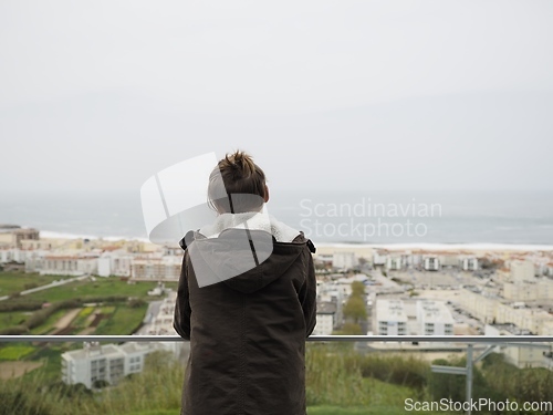 Image of Teenager in a jacket standing in a balcony