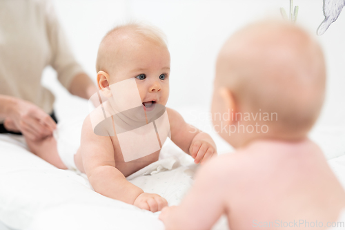 Image of Beautiful shot of a cute baby boy looking at his reflection in big mirror.
