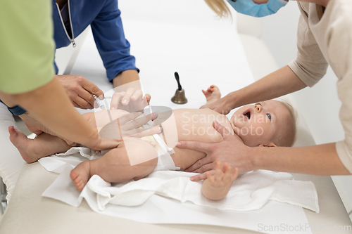 Image of Baby beeing vaccinated by pediatrician in presence of his mother. Preventive vaccination against Diphtheria, whooping cough, tetanus, hepatitis, haemophilus influenzae, pneumococcus, poliomyelitis