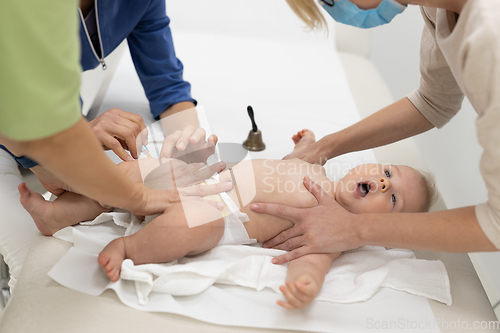 Image of Baby beeing vaccinated by pediatrician in presence of his mother. Preventive vaccination against Diphtheria, whooping cough, tetanus, hepatitis, haemophilus influenzae, pneumococcus, poliomyelitis