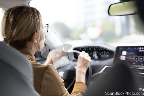 Image of Business woman driving a car to work. Female driver steering car on the road
